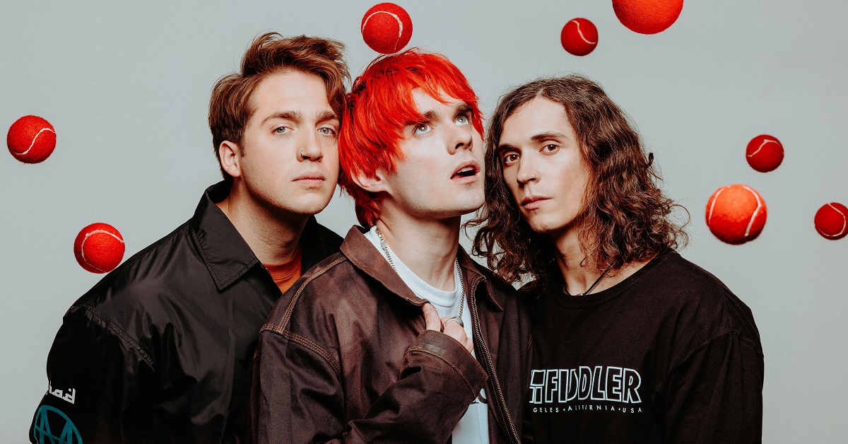 A photo of Waterparks, with red tennis balls above their heads