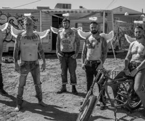 A photo of Avenged Sevenfold in a trailer park, they are wearing no tops and have wings on their back. 